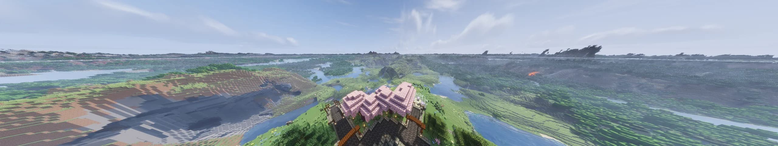 A very wide view from above spawn's cherry trees: rivers, lakes, forest and bare hills stretching away to mountains on the horizon, far beyond Minecraft's normal render distance.